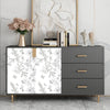 A gray dresser with a white floral peel-and-stick wallpaper panel and gold hardware, displayed against a white wall.