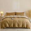 A beige quilted duvet cover set with matching pillowcases displayed on a bed against a light wall.