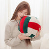 A woman holds a red and green simulation volleyball plush toy pillow.