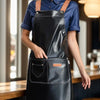 A woman wearing a black PU leather multi-pocket kitchen apron over a blue shirt.
