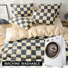 A checkered print bedding set with a duvet cover and pillows displayed next to a white washing machine.