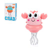 A pink interactive dancing crab toy with large eyes and wavy legs is shown next to its packaging.