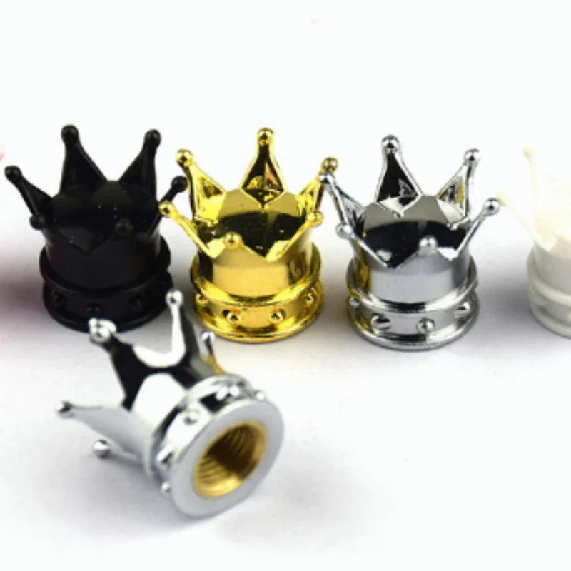 A set of four metal crown valve caps in black, gold, silver, and silver are displayed on a white background.