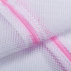 Close-up of a white mesh laundry bag with a pink zipper detail.