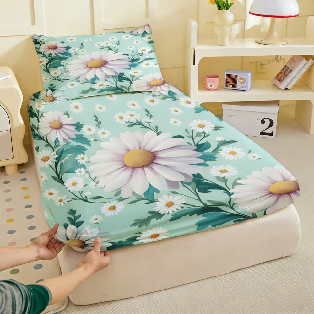 A light teal fitted sheet featuring a white daisy print is laid out on a cream-colored surface.