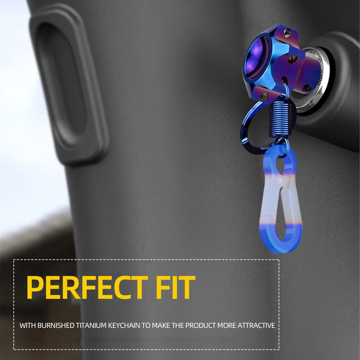 A close-up of a motorcycle key head cover with a blue titanium keychain attached to a dark surface.