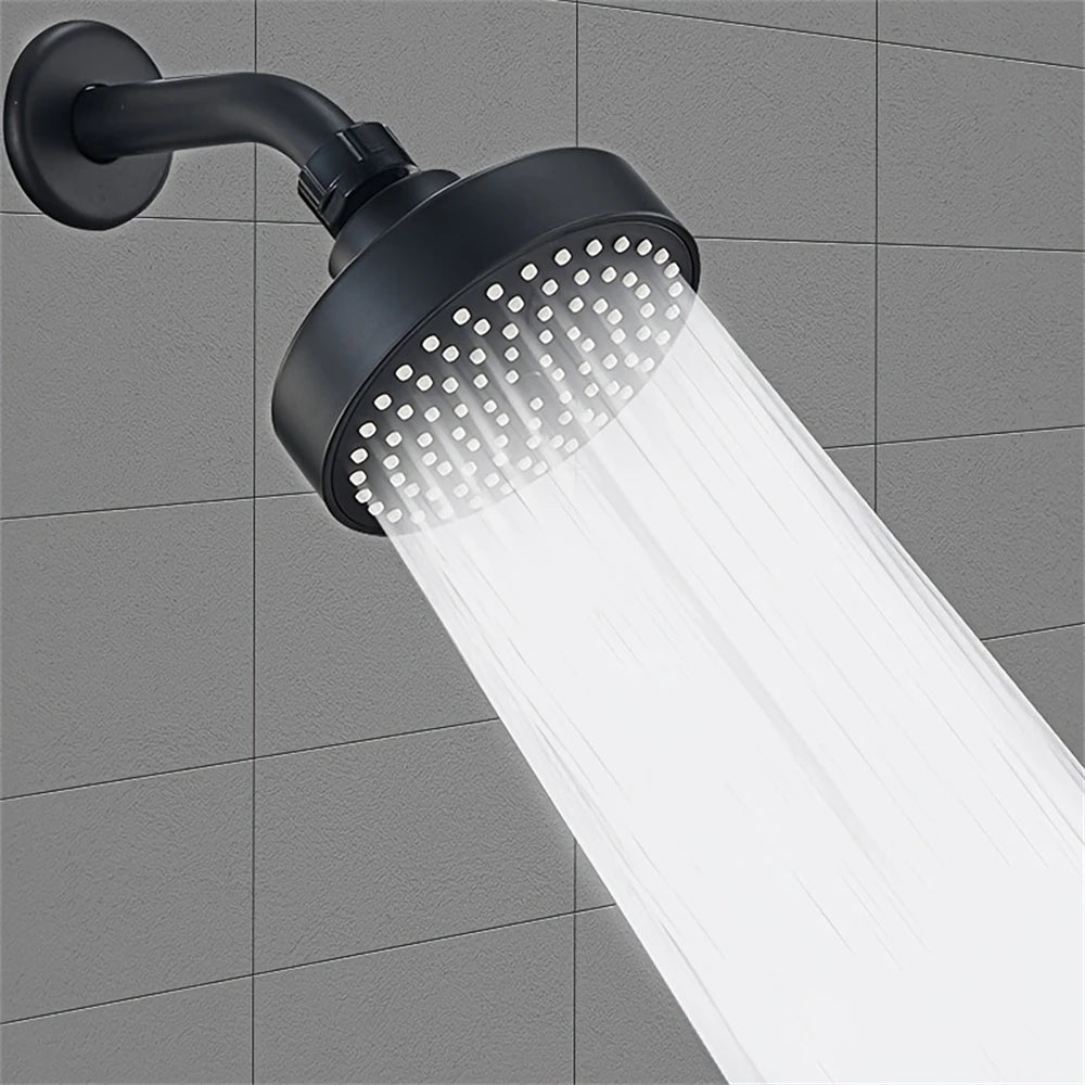 A matte black shower head is mounted on a wall, emitting a strong stream of water.
