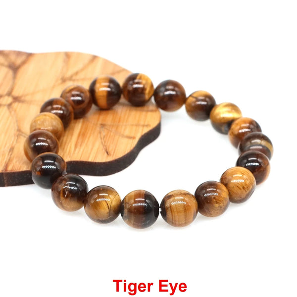 A bracelet made of Tiger Eye beads is displayed on a wooden slice.