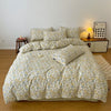 A beige and yellow floral printed duvet cover set with pillows displayed on a bed in a bright room.