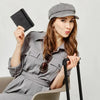 A woman holds an RFID blocking leather card holder and passport wallet while seated.