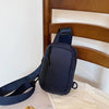 Dunkelblaue Crossbody-Tasche mit schwarzem Riemen auf einem Holzbettrahmen.