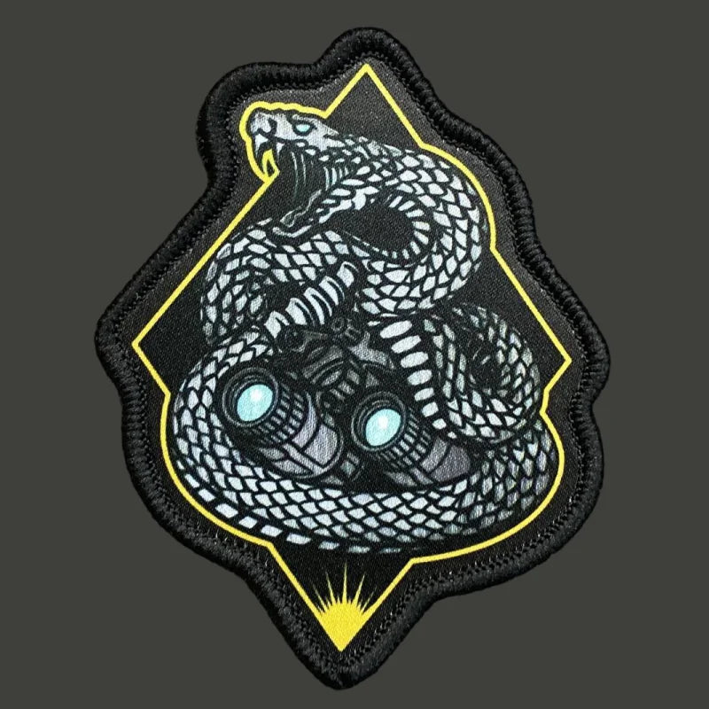 A black tactical snake morale patch featuring a detailed gray and white coiled snake design with yellow accents.