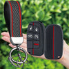 A black silicone key fob cover with a red stripe and a metal ring is shown being held by a hand.