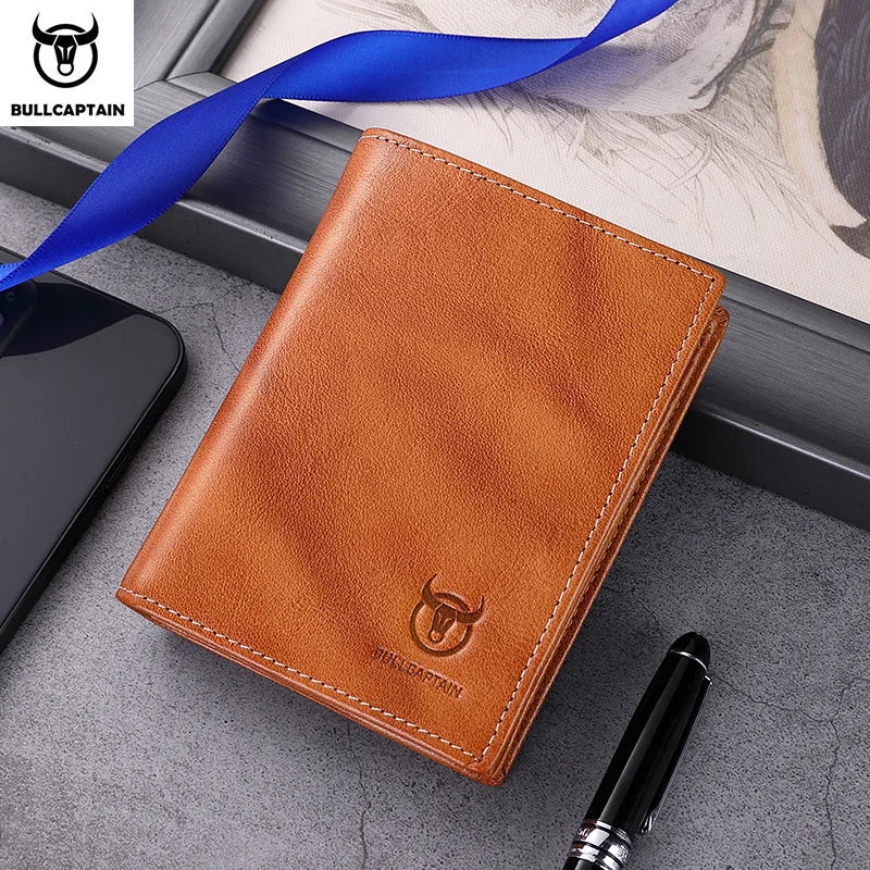 A brown genuine leather men's bifold wallet with stitching and a logo, placed next to a black pen.
