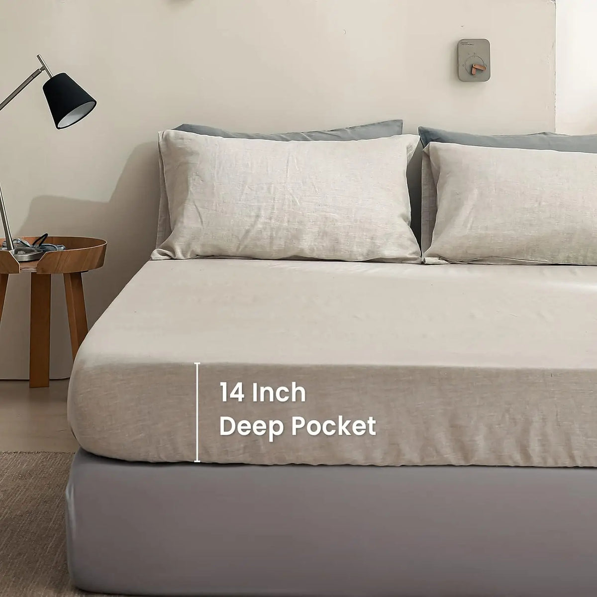 A close-up of a beige linen fitted sheet with 14 inch deep pockets on a bed.