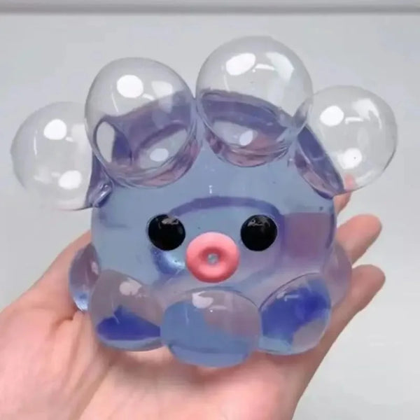 Eine Hand hält einen durchsichtigen lila und blauen sensorischen Stressball mit runden, aufgeblasenen Blasen.