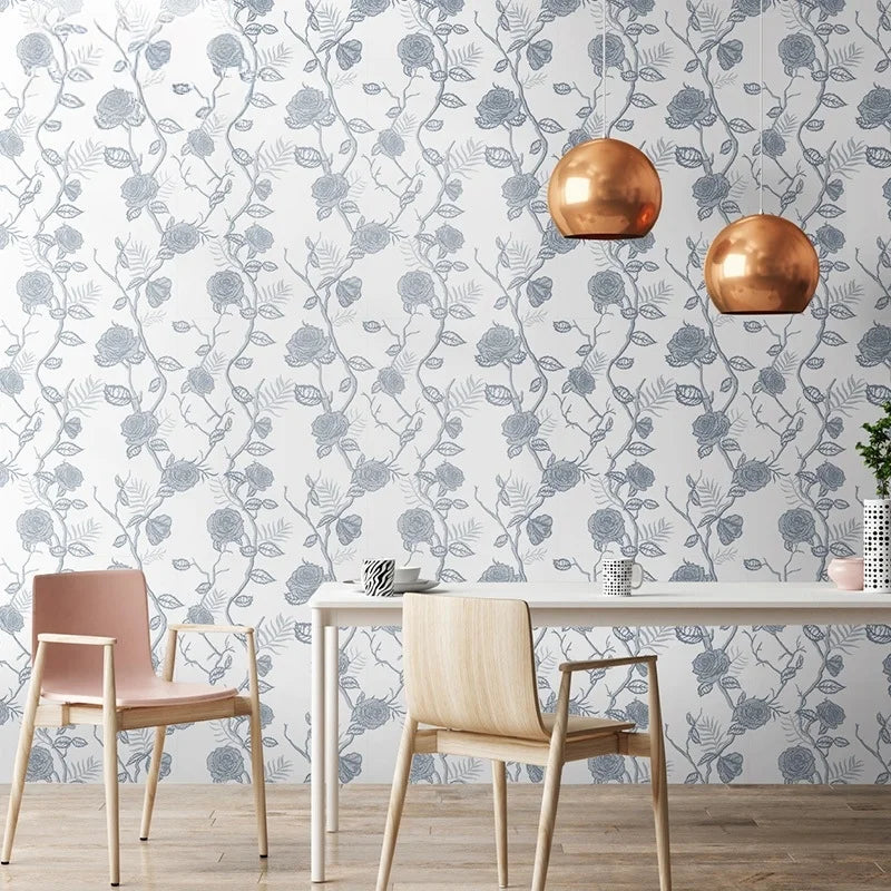 A modern dining room wall featuring a gray and white botanical leaf wallpaper with round gold decorative objects.