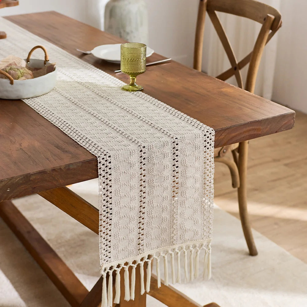 Beige boho table runner with tassels hand-woven farmhouse style placed on a wooden table.