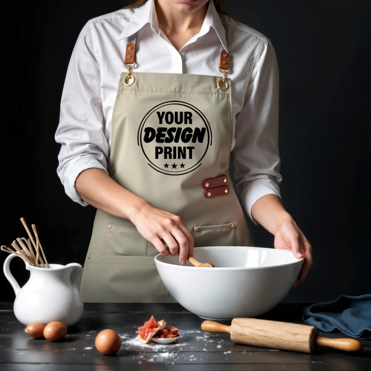 A person wearing a beige canvas apron with a circular design is shown next to kitchen tools and ingredients.