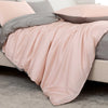 Luxuriöses rosa Bambus-Duvetcover-Set mit grauen Akzenten über einem Bett drapiert.
