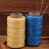 Two spools of waxed polyester thread in yellow and blue colors with sewing needles