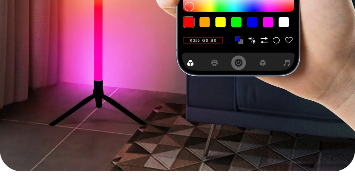 A hand holds an RGB LED floor lamp, showing a color wheel interface on the device.