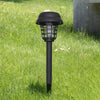 A black solar-powered mosquito zapper with an ambient light is installed in a green lawn.