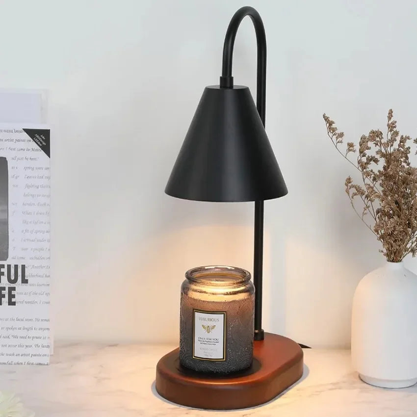A black electric candle warmer lamp with a conical shade and wooden base sits on a white surface.