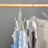 A wooden rod holds a multi-layered hanging organizer with various colored fabric items like hats and scarves.