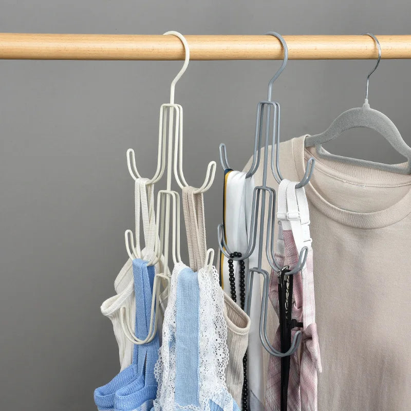 A wooden rod holds a multi-layered hanging organizer with various colored fabric items like hats and scarves.