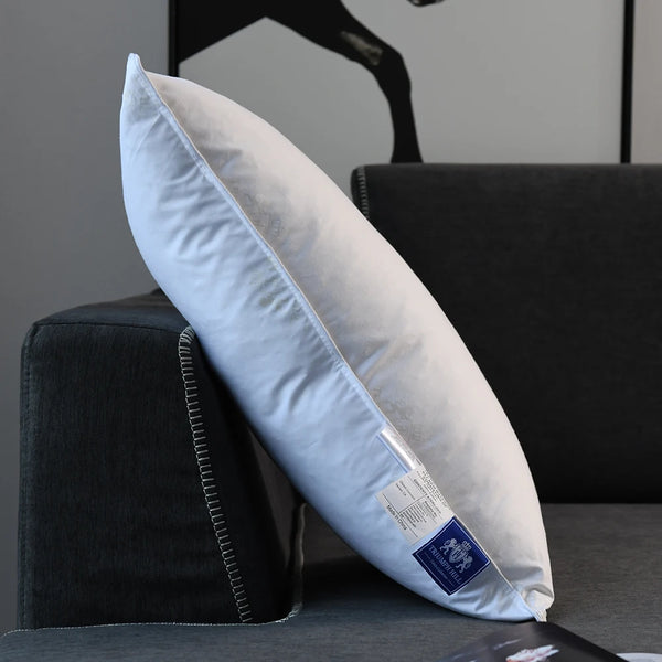 A light blue cushion pillow with white stitching resting on a dark surface.