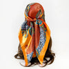 A vibrant orange and blue leopard paisley square scarf tied around a dark hair