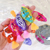 A hand holds several colorful light-up sensor swimming fish toys in water.