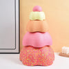 A stack of colorful, textured balance stepping stones in pink, orange, and yellow on a white surface.
