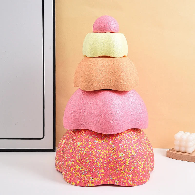A stack of colorful, textured balance stepping stones in pink, orange, and yellow on a white surface.