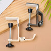 A set of foldable aluminum desk hooks with black grips and light wood accents shown on a wooden surface.