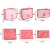 Six pink fabric laundry pouches and packing cubes of various sizes displayed side by side.