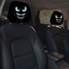 A pair of black car headrest covers featuring creepy, snarling monster faces with glowing green eyes.
