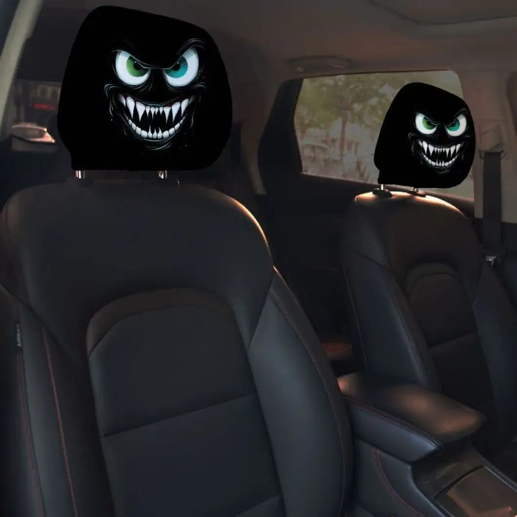 A pair of black car headrest covers featuring creepy, snarling monster faces with glowing green eyes.