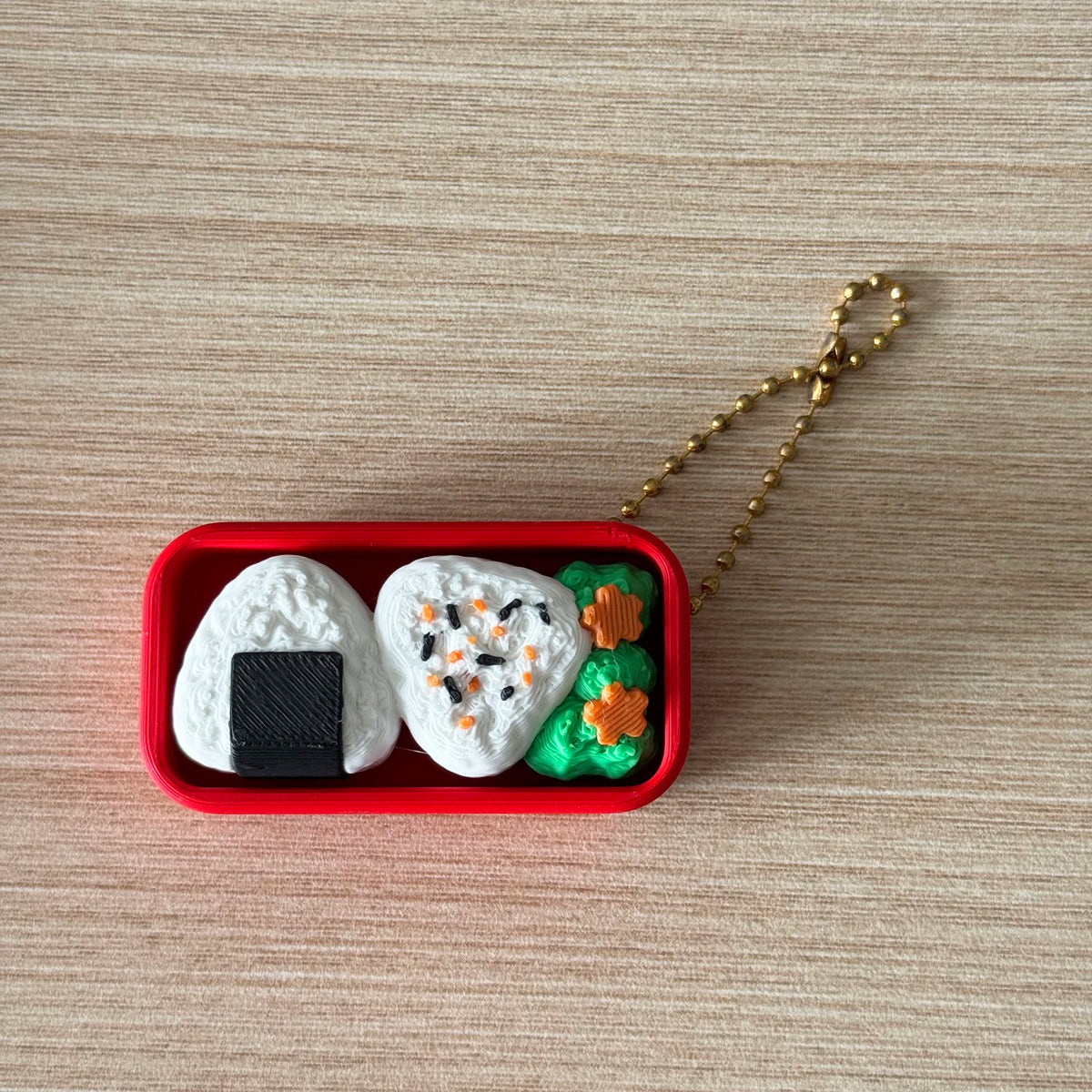 A red container holds a white cake-shaped fidget keychain with black icing and green decorations.