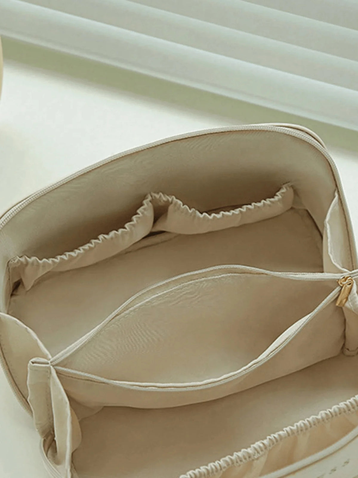 A light beige leather travel makeup organizer bag shown open with a soft lining and drawstring closure.