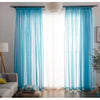 Light blue sheer voile curtains hanging in a window with white light filtering through