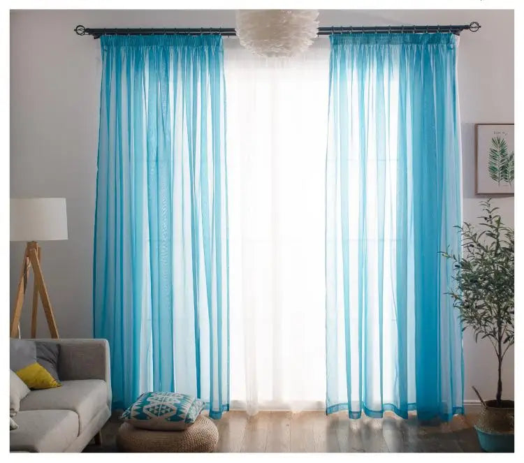 Light blue sheer voile curtains hanging in a window with white light filtering through