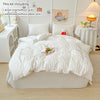 A white lightweight seersucker duvet cover set including a duvet cover, pillowcases, and decorative items displayed on a bed.