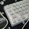 A close-up view of translucent PC keycaps for a mechanical keyboard, showing various keys and a pearl necklace.