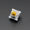 A close-up view of a white plastic 3-pin mechanical keyboard switch with a yellow housing.