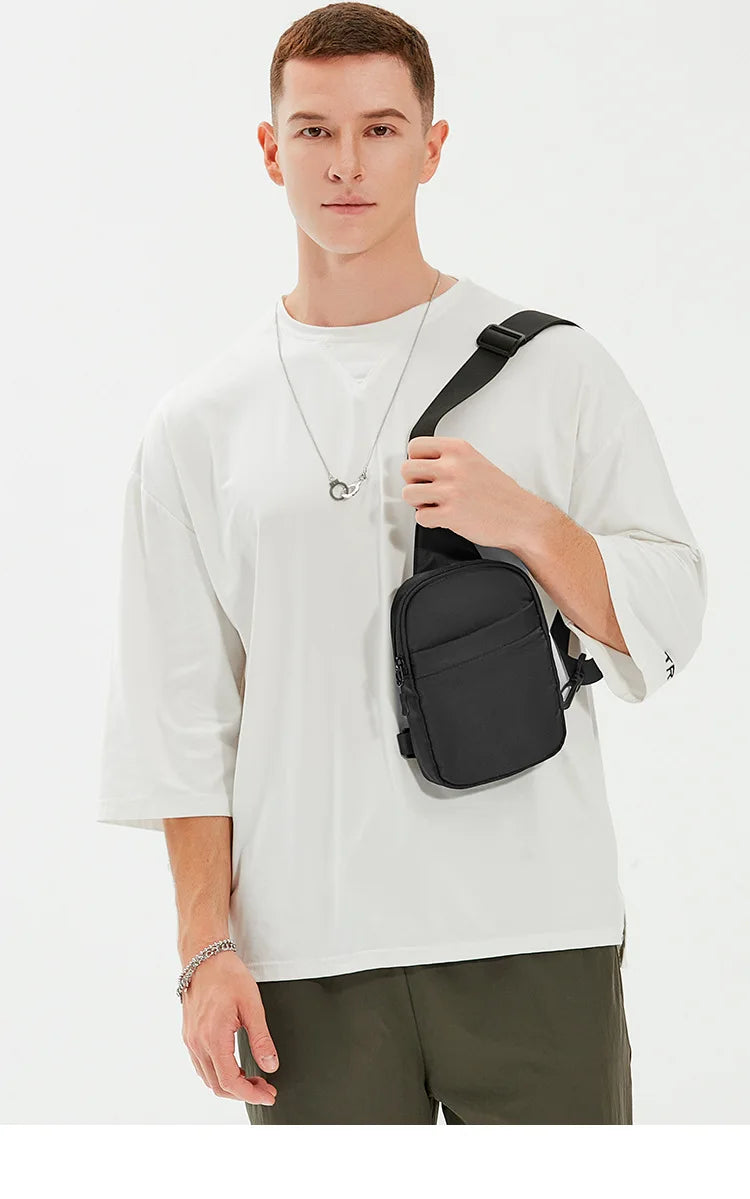 A male model wearing a white t-shirt and olive pants, holding a black convertible sling bag.
