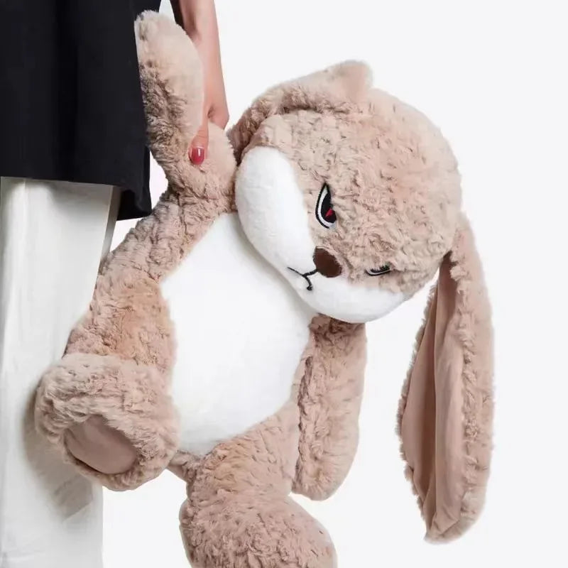 A fluffy, light brown angry rabbit plush toy with long ears is being held by a person.