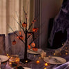 An LED Halloween birch tree decorated with orange and purple lights on a dark surface.