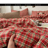 A close-up of a red and green plaid duvet cover set being held by a hand, showing the texture and pattern of the fabric.